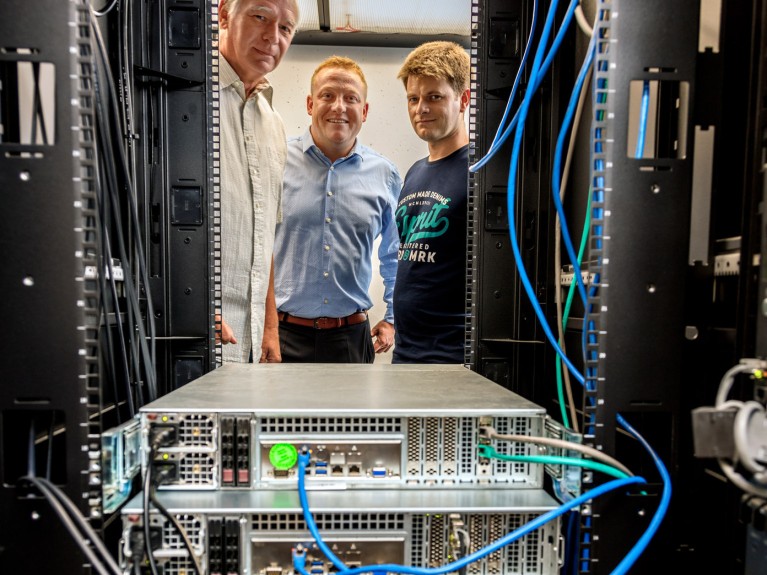 Drei Männer schauen in einen klimatisierten Serverschrank
