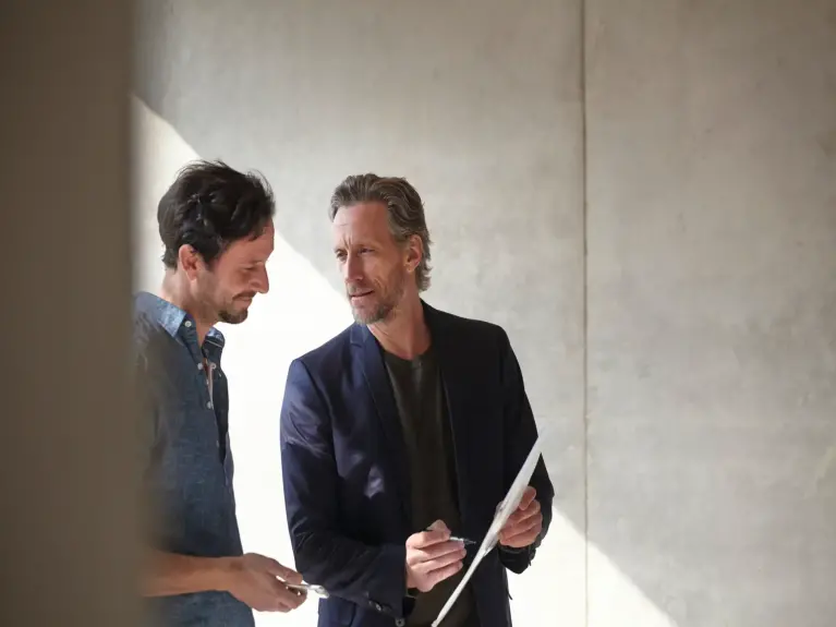 Two people are discussing a document in a modern building.