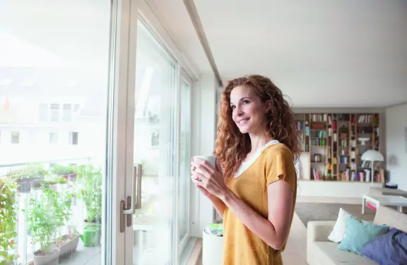 Titelbild Filter Klimaanlagen, Frau mit Kaffe am Fenster