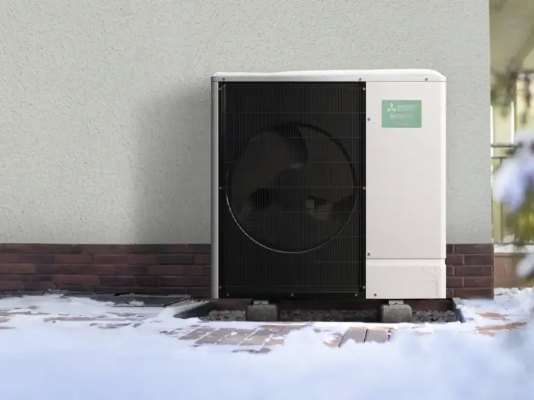 Foto eines Ecodan Außengeräts vor einem Haus im Schnee