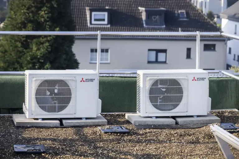 Mehrfamilienhaus mit installierten Wärmepumpen-Außeneinheiten zur energieeffizienten Modernisierung