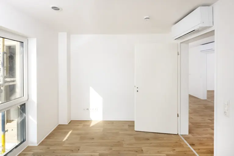 Leerer Wohnraum mit Holzfußboden und M-Serie Wandgeräte nach Sanierung im Dachgeschoss eines Mehrfamilienhauses
