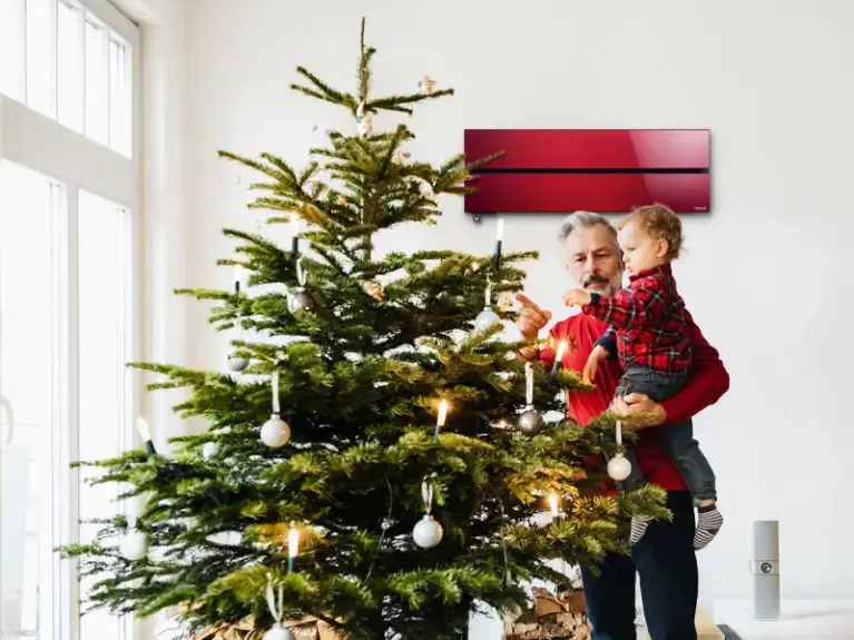 Vater mit Kind auf dem Arm steht am Weihnachtsbaum