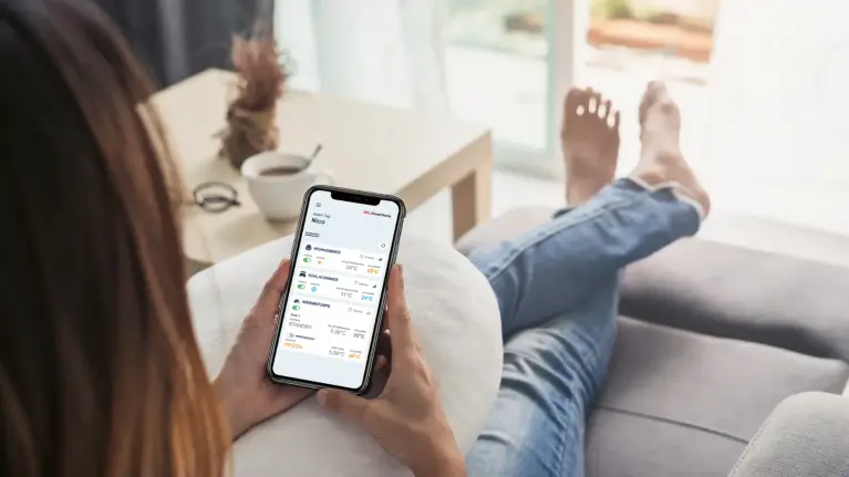 Frau mit Smartphone und darauf geöffneter MELCloud Home App in der Hand