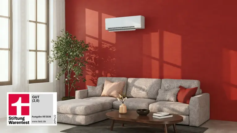 Logo Testsieger Stiftung Warentest MSZ-RZ vor einer Einbau-Situation eines Schlafzimmers. Eine Frau Sitzt auf dem Bett, im Hintergrund die Wand mit weißem Wandgerät MSZ-RZ.