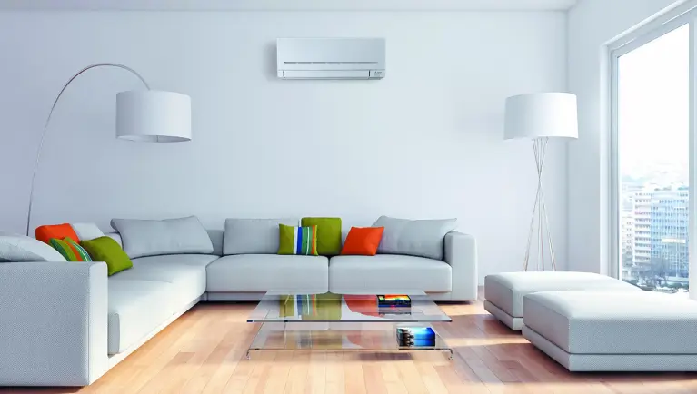Ein helles Wohnzimmer mit grauen Sofas und Mitsubishi Electric Wand-Klimagerät