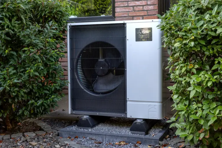 Foto eines Ecodan Außengeräts zwischen Hecken