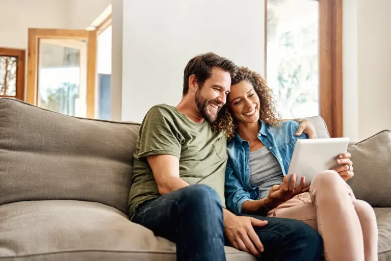 Couple sitting on a couch in front of a tablet