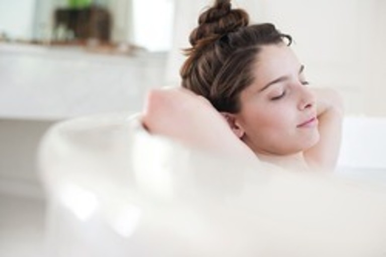Beeld van een ontspannen vrouw in een badkuip