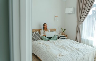 Vrouw zit op bed met laptop