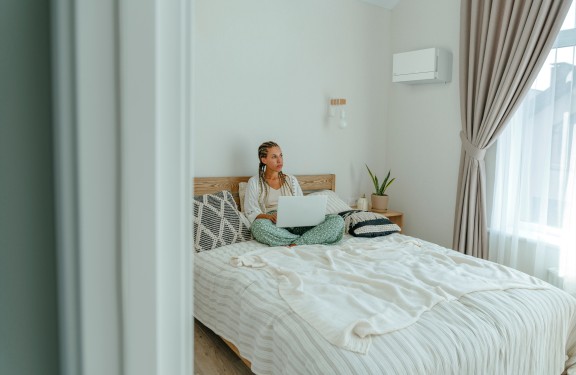 Vrouw zit op bed met laptop