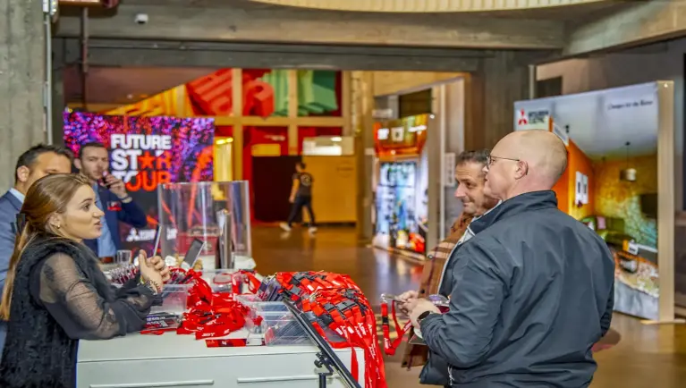Twee medewerkers van Mitsubishi Electric delen de badges uit bij de inkom