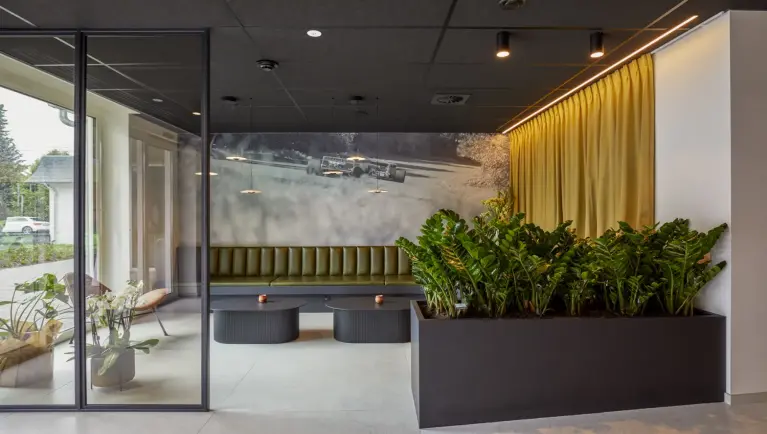 Ruimte met olijfgroene bank en twee zwarte ovale tafels