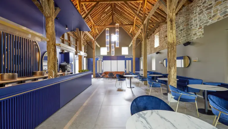 Zitruimte met blauw stoelen en marmeren tafels, aan de zijkant is er een blauwe bar