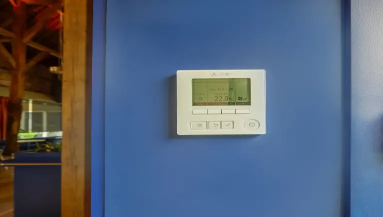 Witte centraal beheersysteem hangt aan blauwe muur