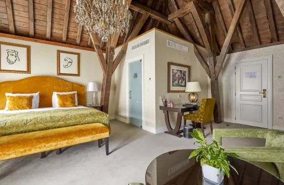 Slaapkamer in Grand Hotel Casselbergh met okergeel bed houten plafond 