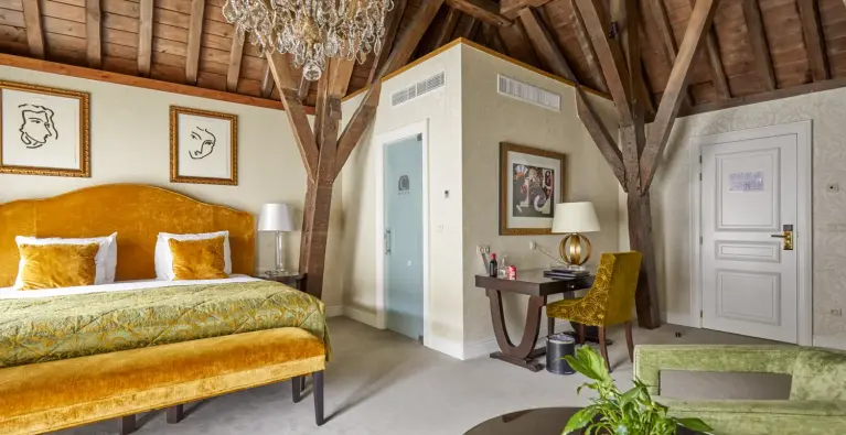 Slaapkamer in Grand Hotel Casselbergh met okergeel bed houten plafond 