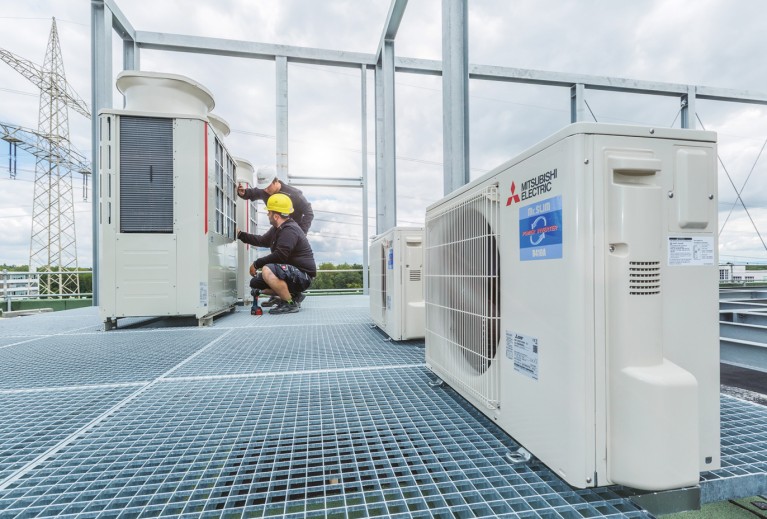 Mannen op het dak bezig met een City Multi Hybrid VRF buitenunit