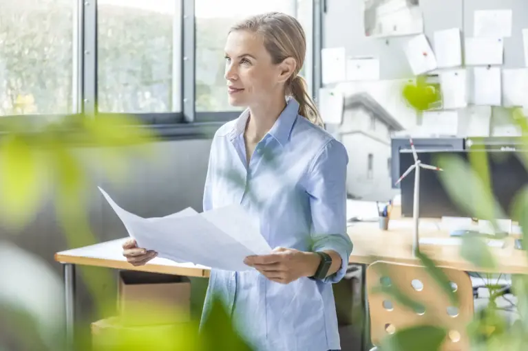 Femme réfléchissant à ses idées d'entreprise en tenant une feuille.