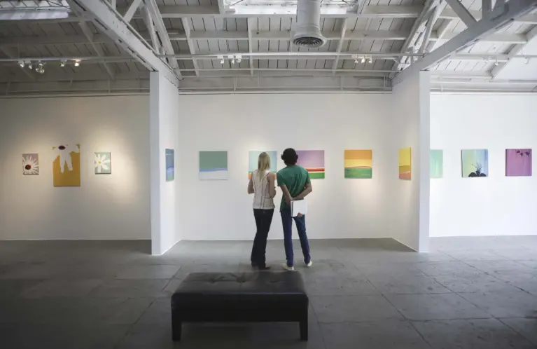 Un homme se tient devant des tableaux dans un musée