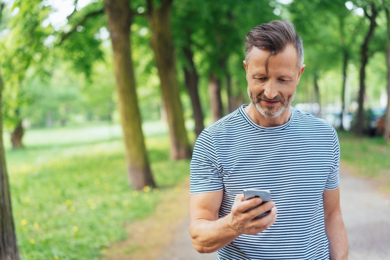 Thomas Miles in het park met een mobiele telefoon in zijn hand