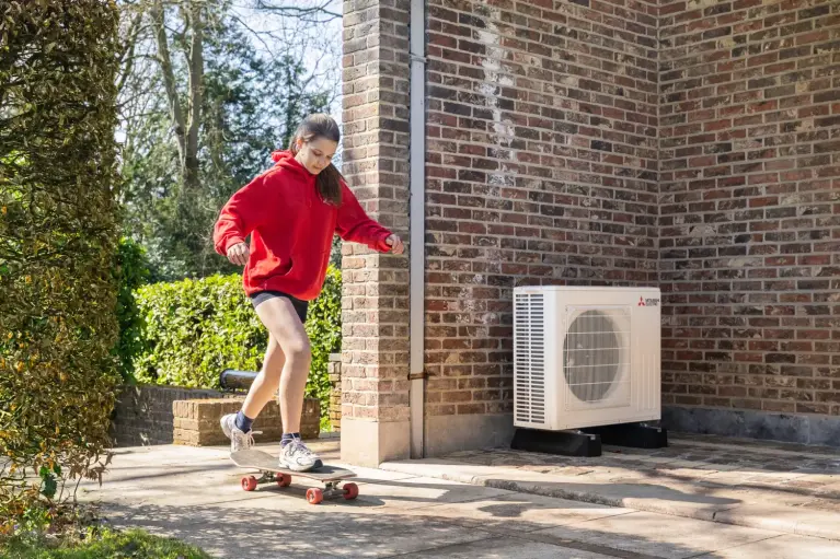 Meisje op skateboard langs warmtepomp