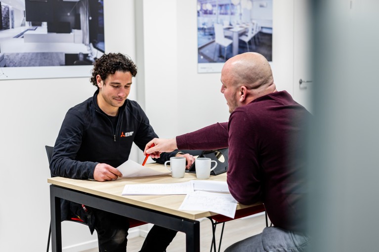 Installateur met zwarte jas pakt een fles uit zijn bestelwagen