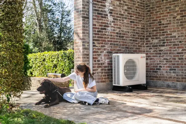 Meisje is haar hond aan het strelen op het terras voor een warmtepomp