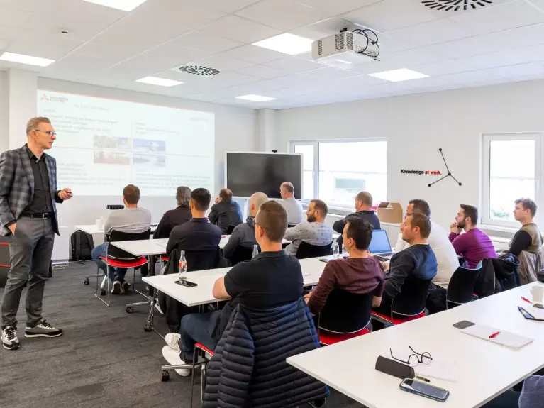 Des installateurs reçoivent une formation dispensée par un spécialiste au centre de formation de Ternat - photo prise de dos