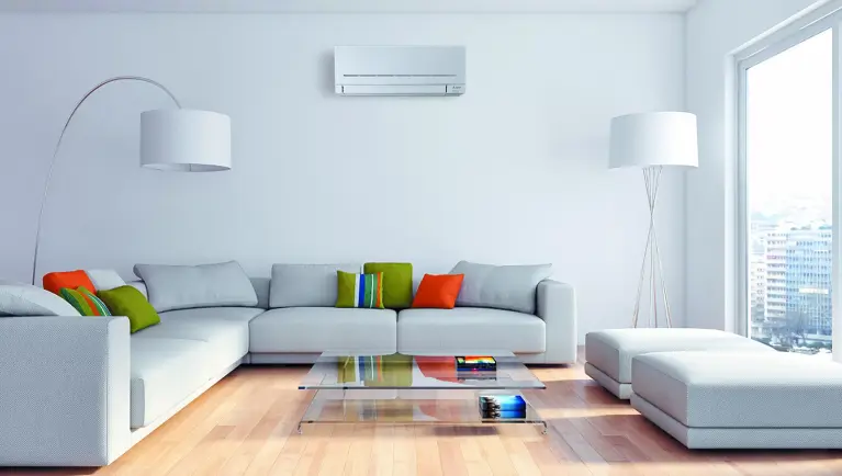 Een lichte woonkamer met grijze banken en Mitsubishi Electric airconditioner aan de muur