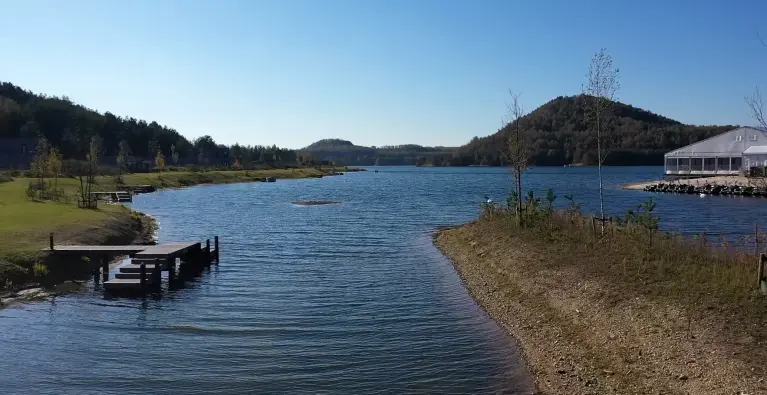 Een blauw uitgestrekt meer met groene heuvels bij Centerparcs Terhills 